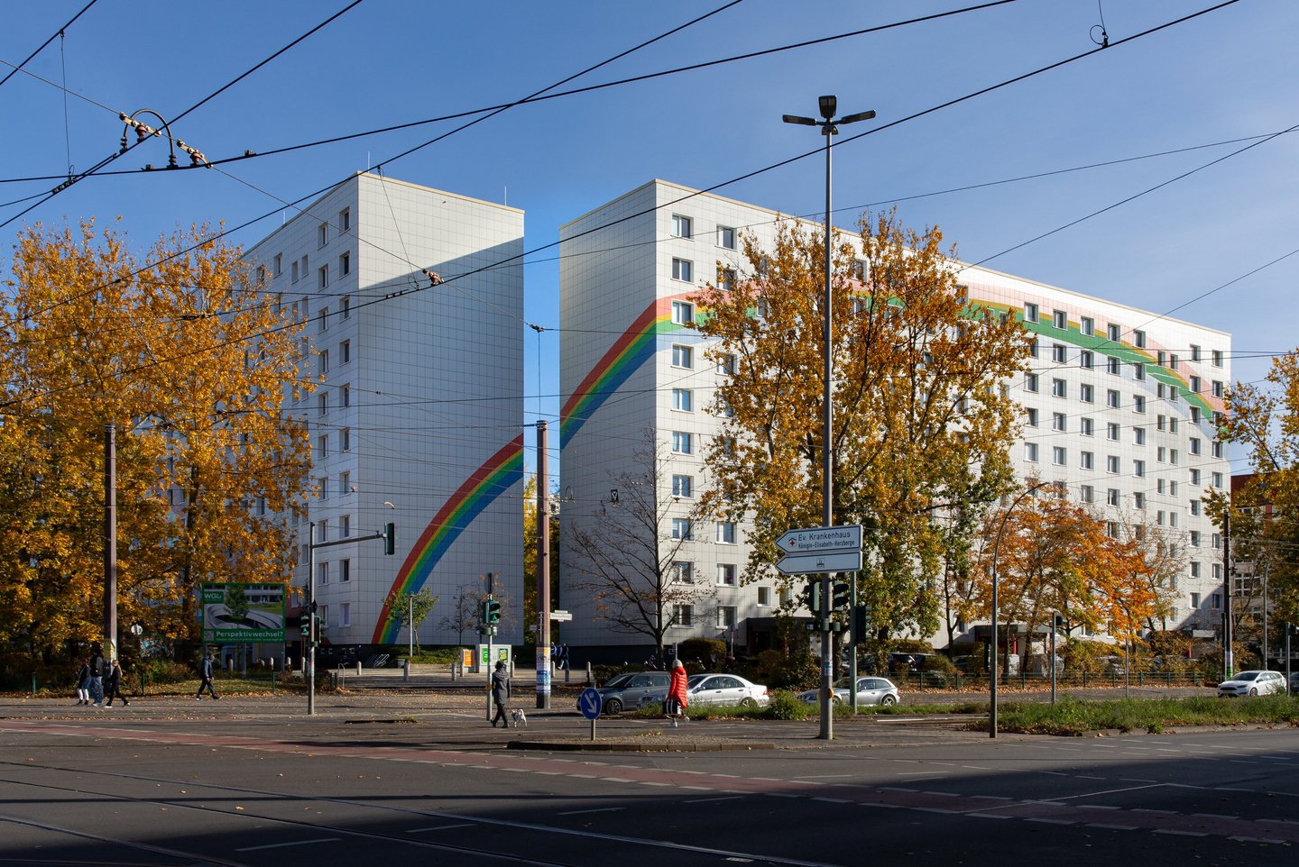 Bild von zwei nebeneinanderstehenden weißen Hochhäusern mit aufgemaltem Regenbogen.
