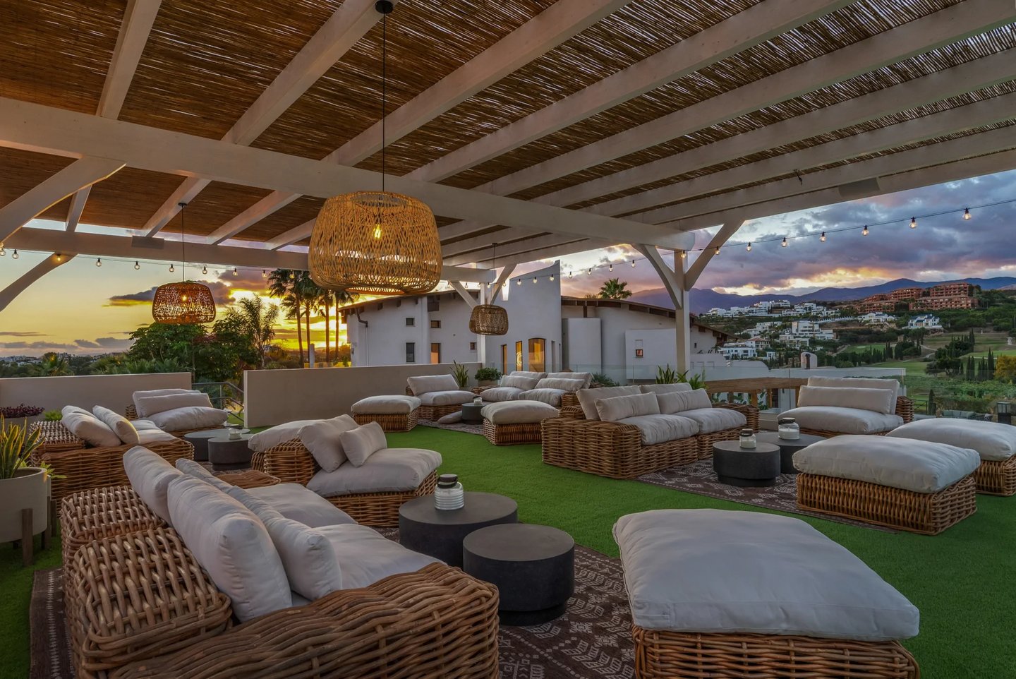Covered rooftop lounge with rattan seating at sunset
