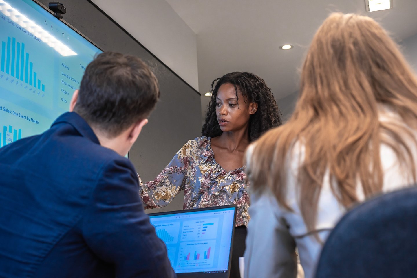 Woman presenting data on a screen to colleagues during a meeting.