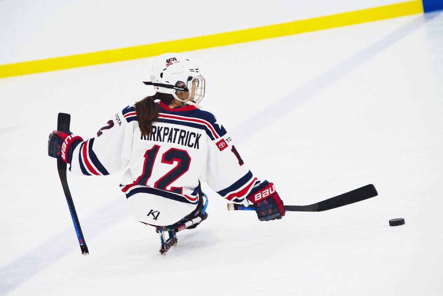 a woman in a hockey uniform is playing sled hockey
