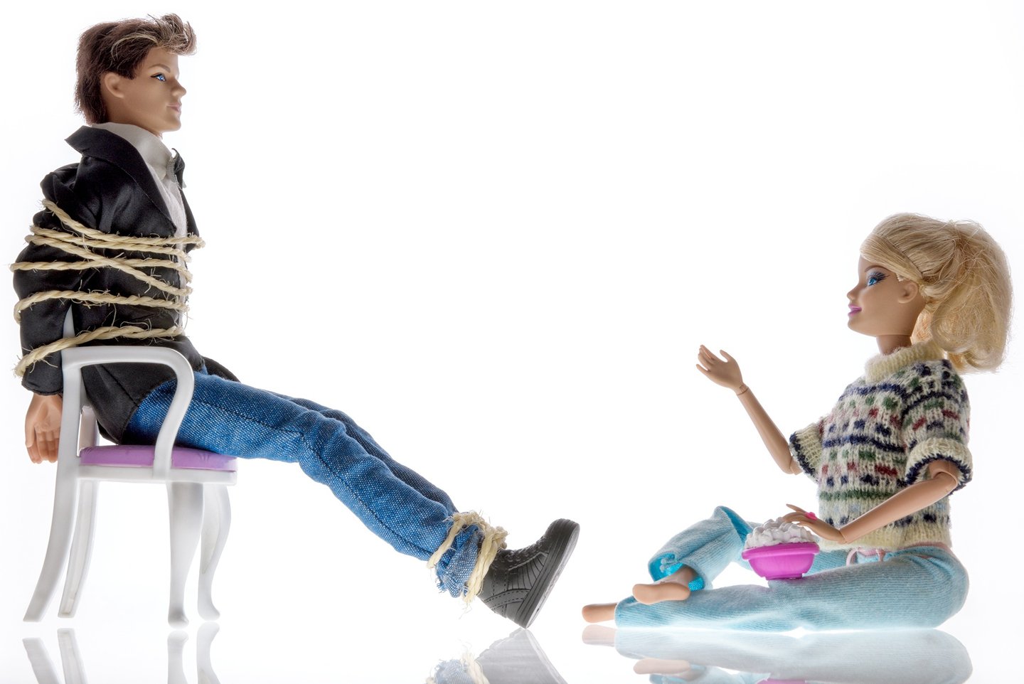 a doll sitting on a floor with a man in a chair