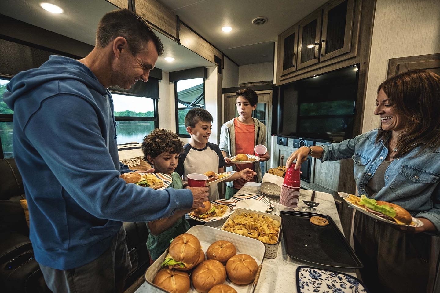 a man, woman, and three children eating a meal in an RV