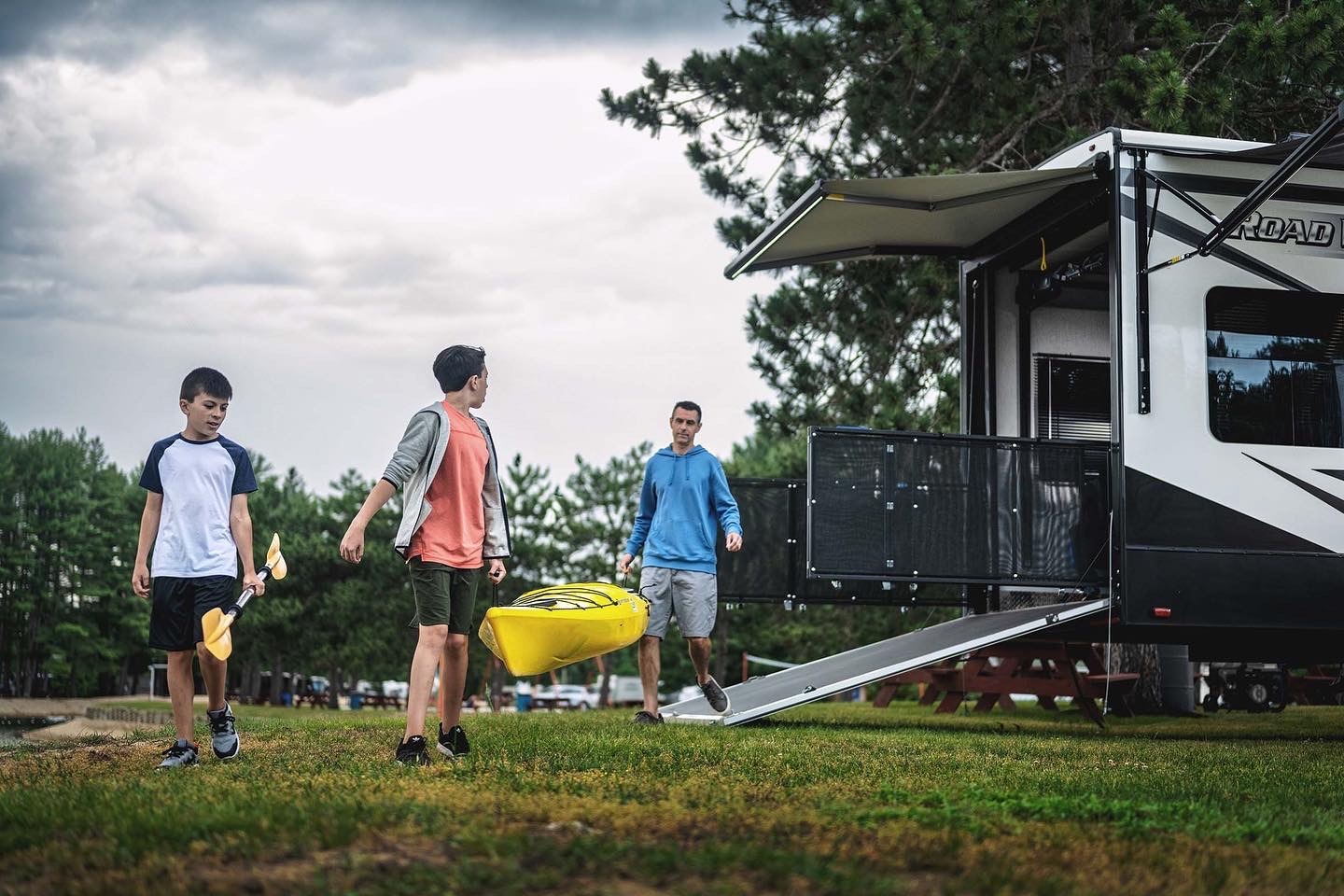 a group of people walking around a trailer carrying a canoe