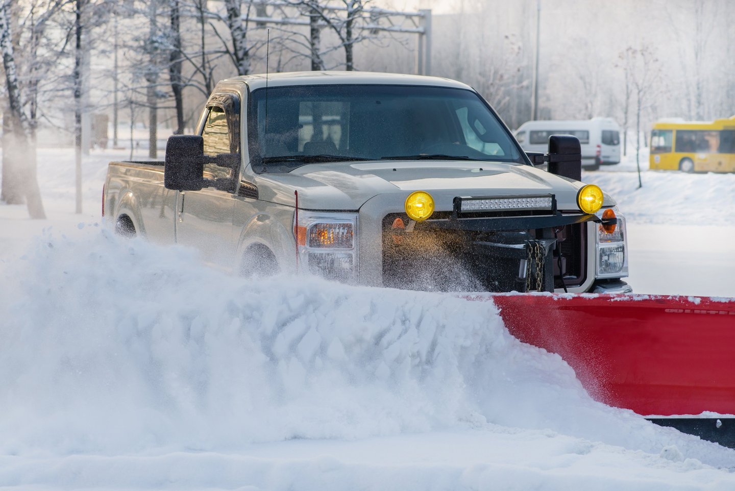 Snowplow truck clearing snow from parking lot after snow storm