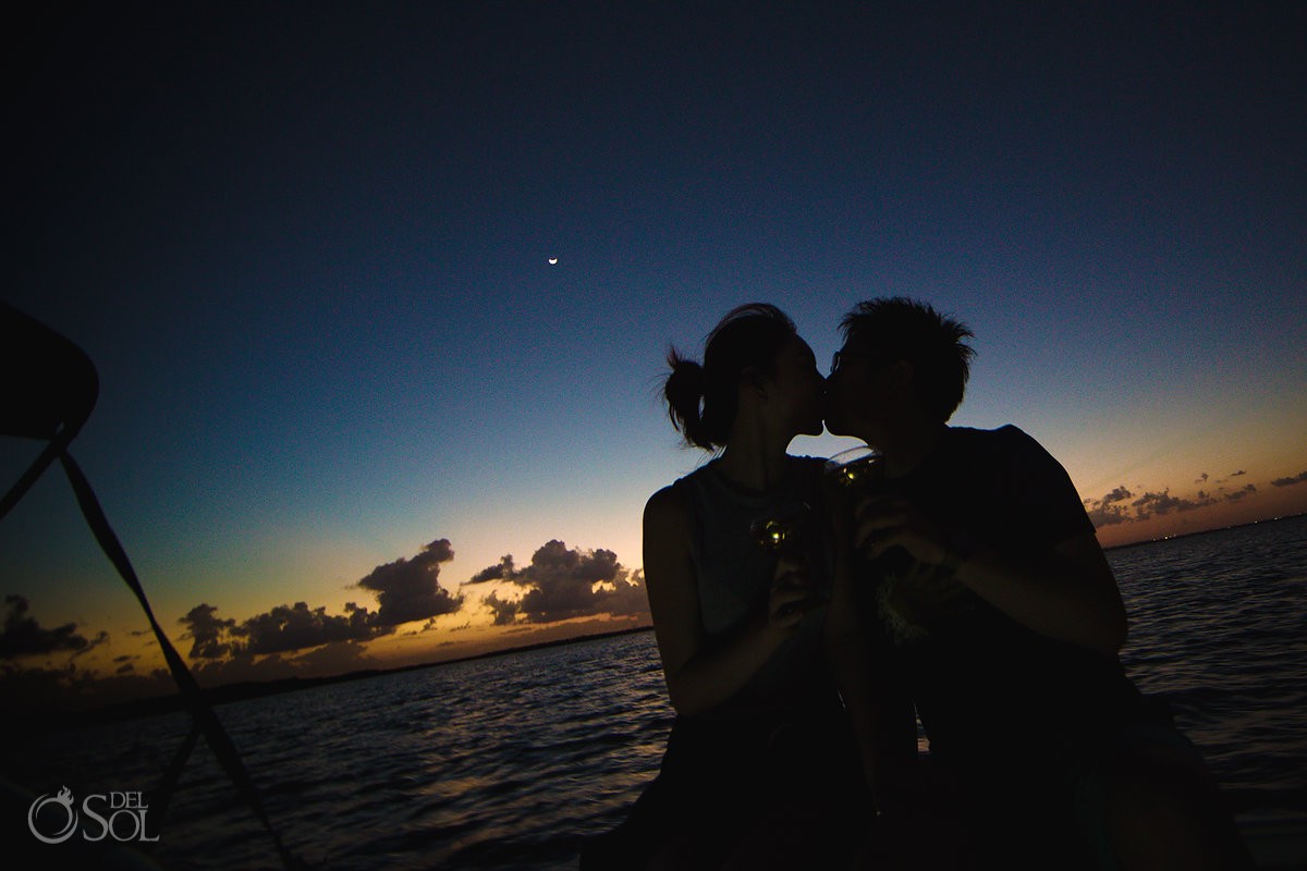 The photo shows a couple kissing on a sunset boat tour.