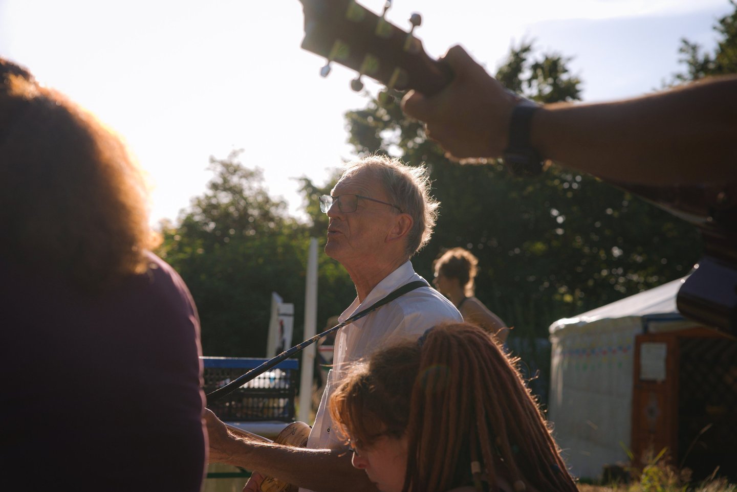 Menschen musizieren zusammen im Sonnenuntergang vor einer Jurte.