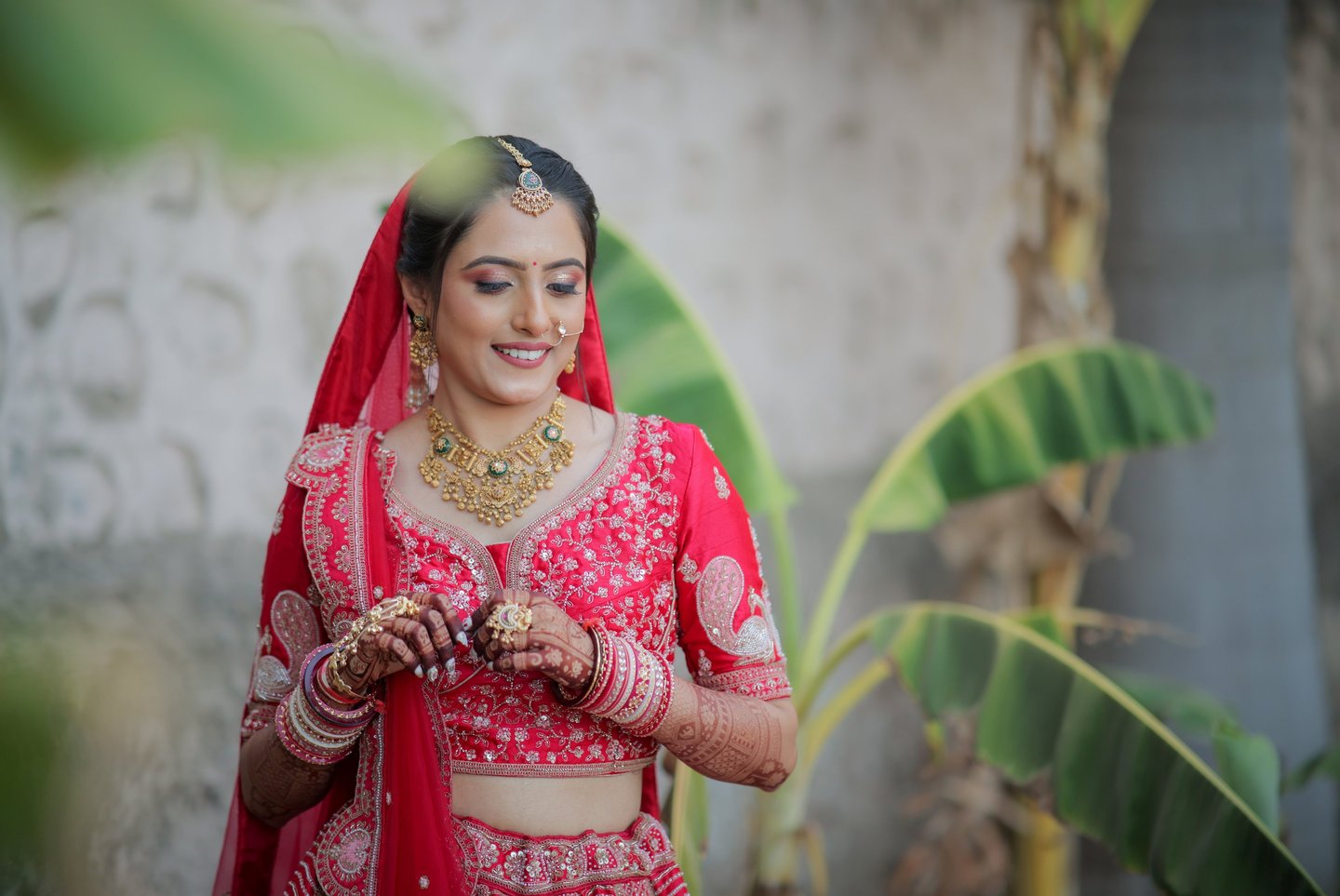 “Bridal portrait of Indian bride in red choli with gold jewellery and mehendi – wedding photography