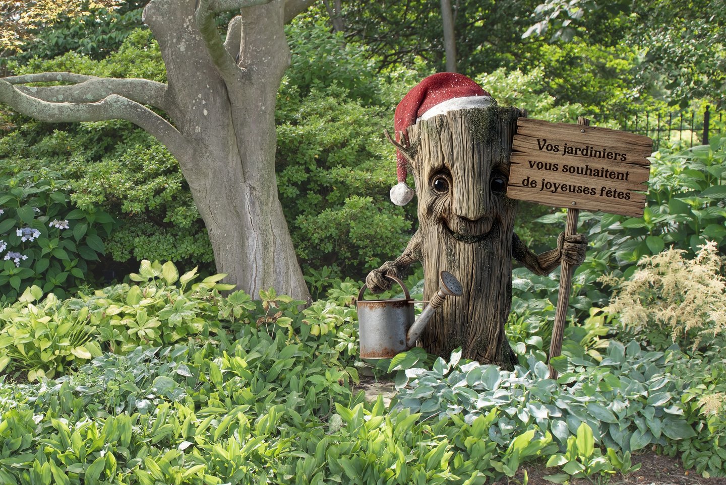 PLV, décoration. Un personnage en tronc d'arbre en PVC qui tient une pancarte dans un jardin.