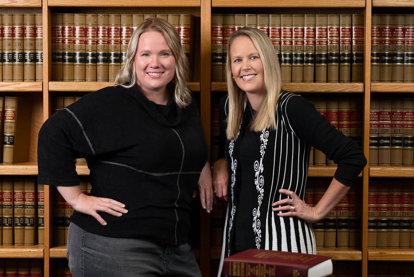 two women standing in front of a bookcase in an office