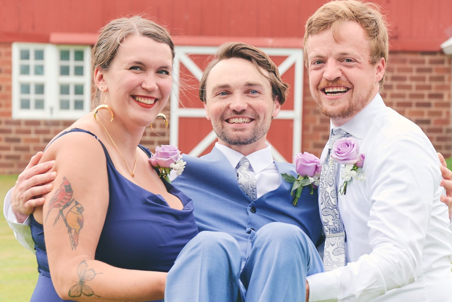 a man and woman carrying a groom for a picture in front of a barn