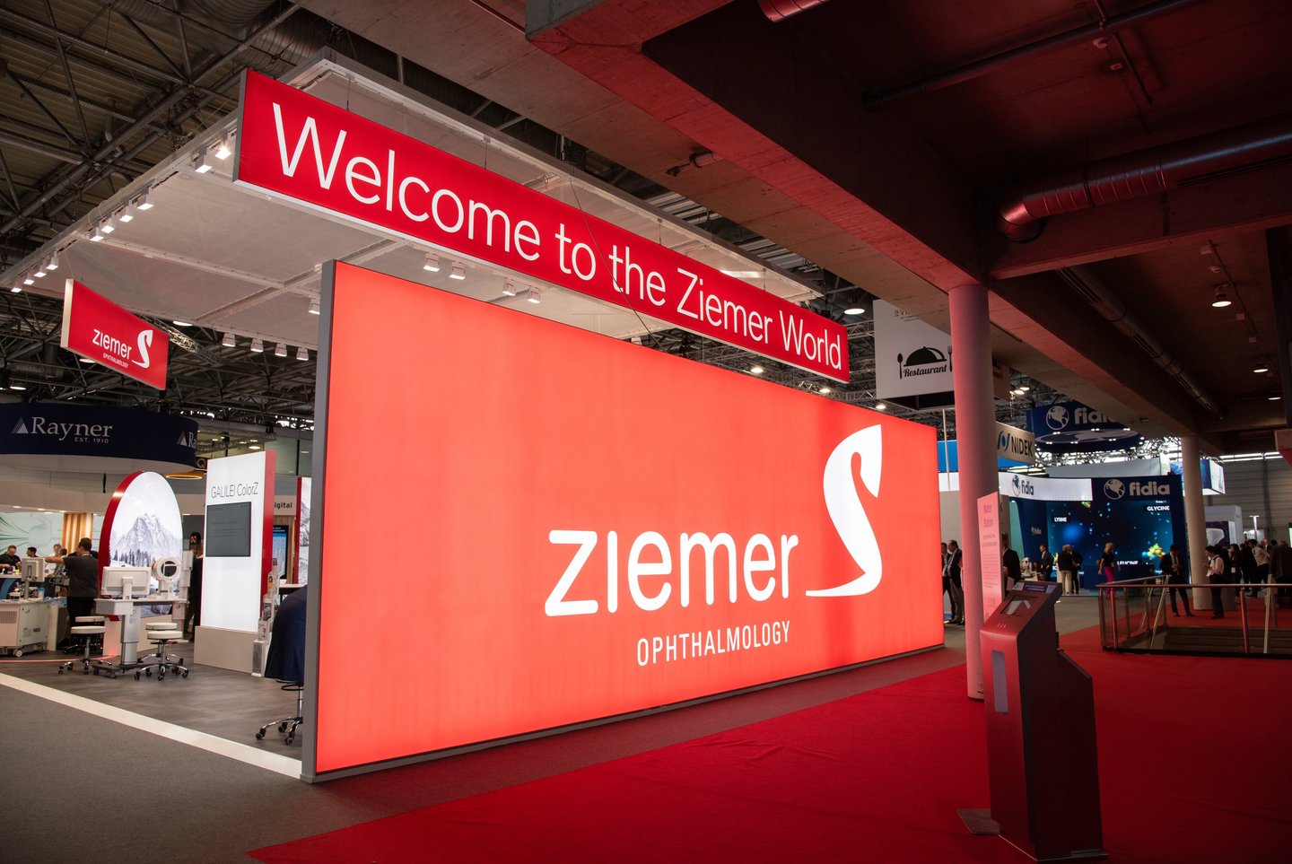 Messestand von Ziemer mit grosser, rot beleuchtetem Logowand auf einer Fachmesse.