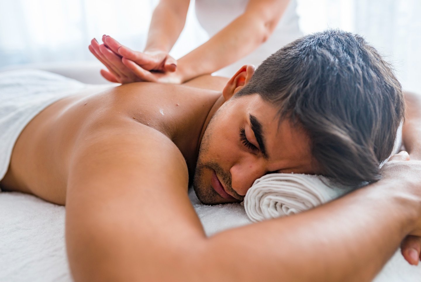 A man receives a relaxing deep tissue back massage from a therapist at a luxury wellness spa.