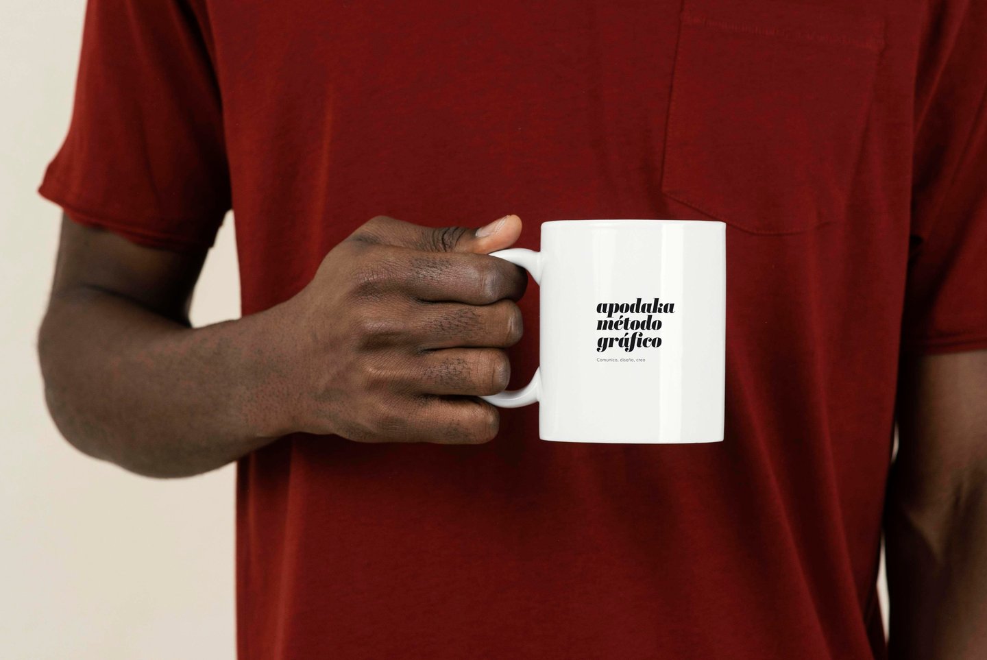 Persona sosteniendo una taza blanca con el logotipo Apodaka Método Gráfico