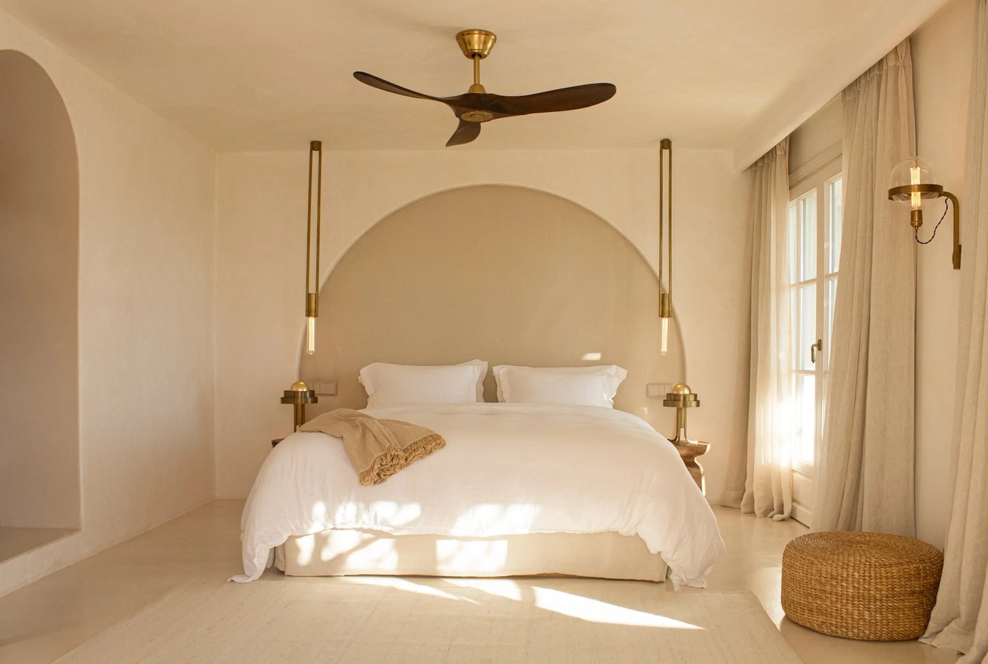 Serene master bedroom with arched headboard and brass lighting