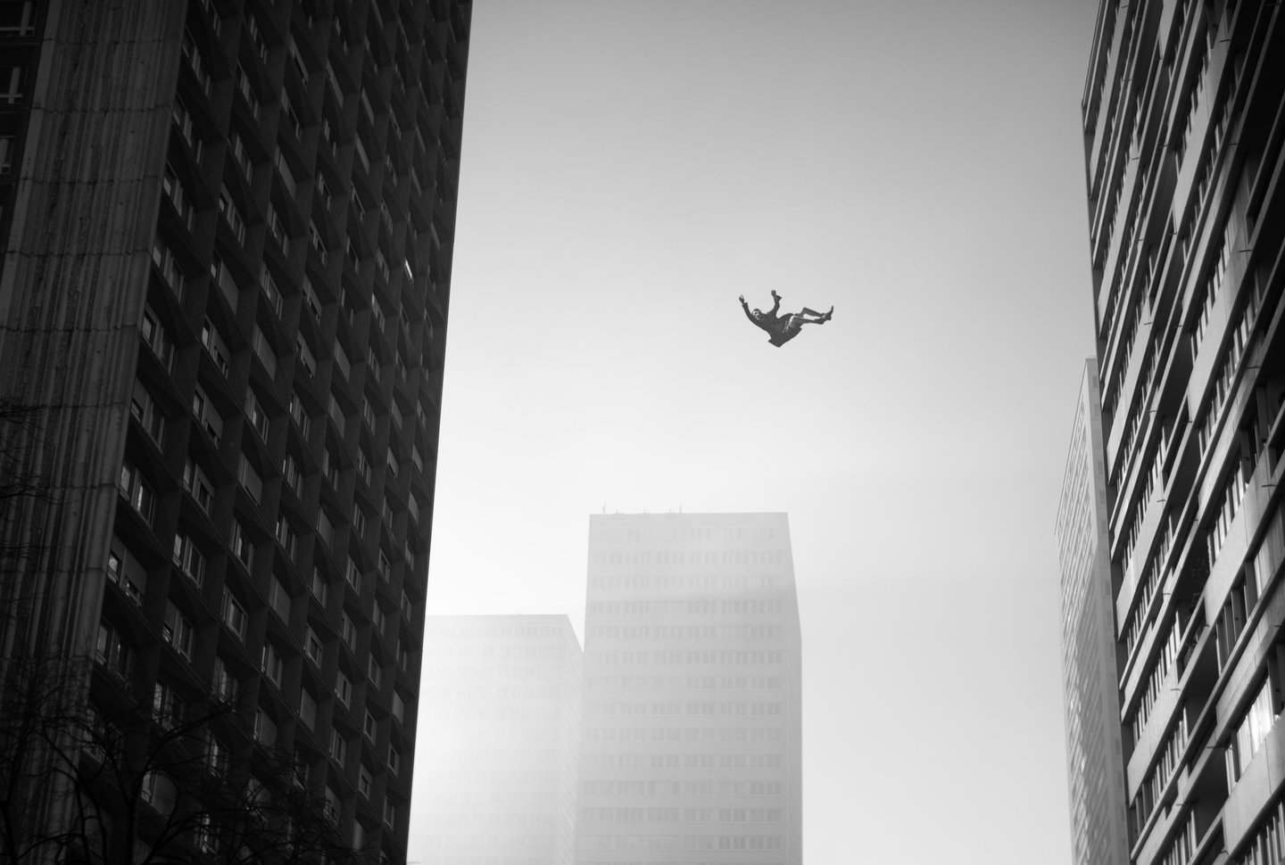 Un homme chute entre des immeubles en noir et blanc