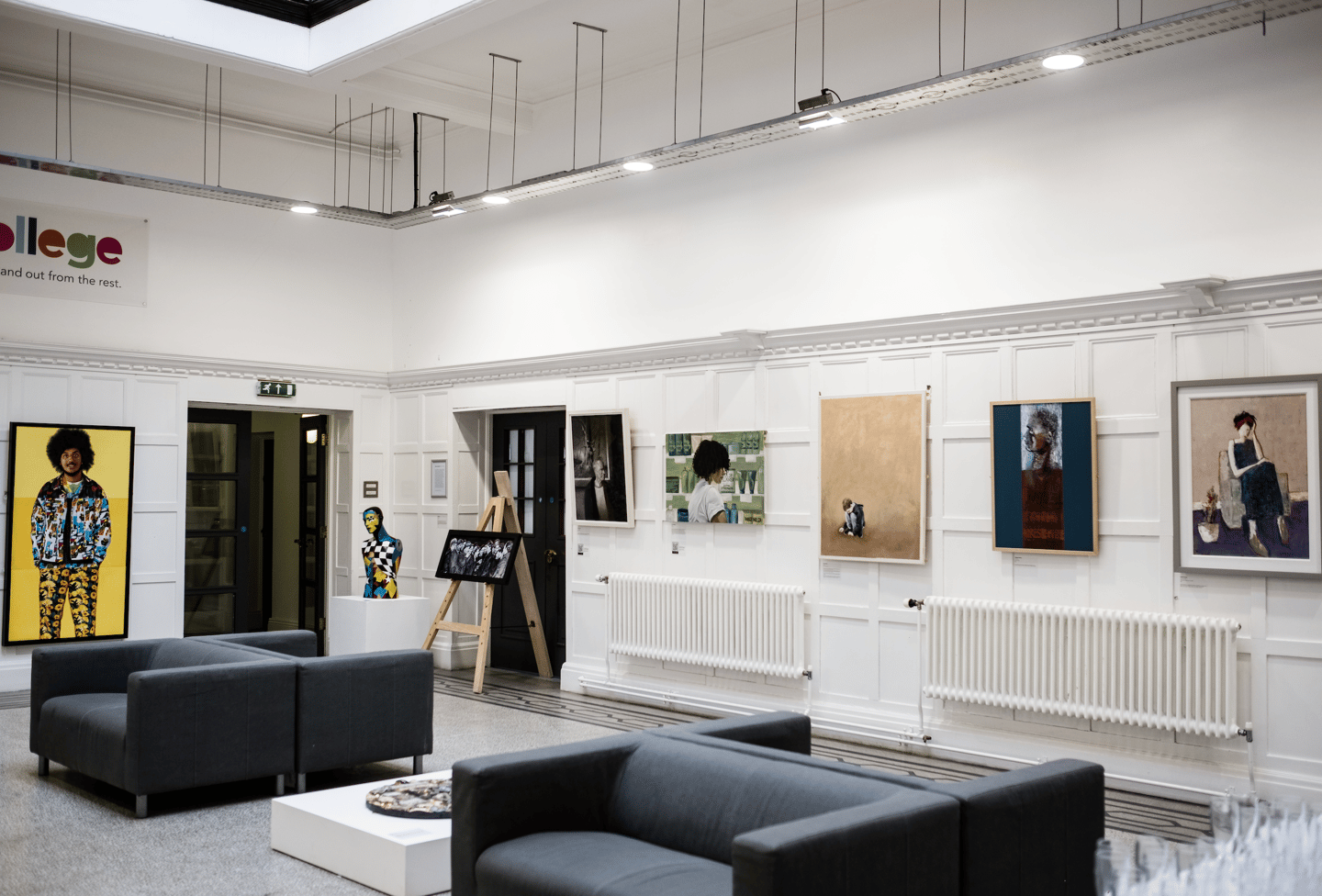 Art work hung in gallery with sofas facing the works.