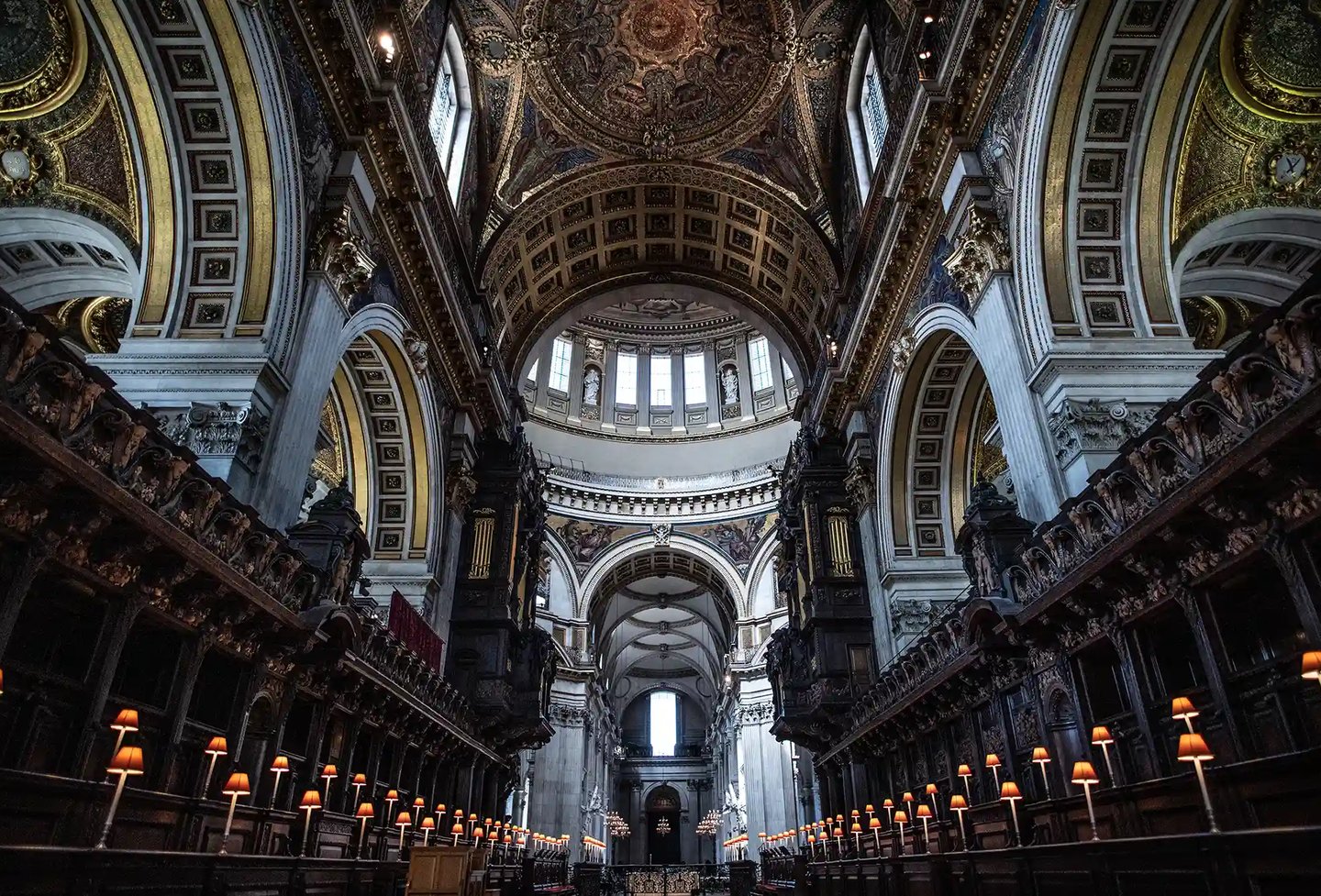 Interior view of St. Paul's Cathedral in London featuring ornate architecture, a high dome, and choir stalls.