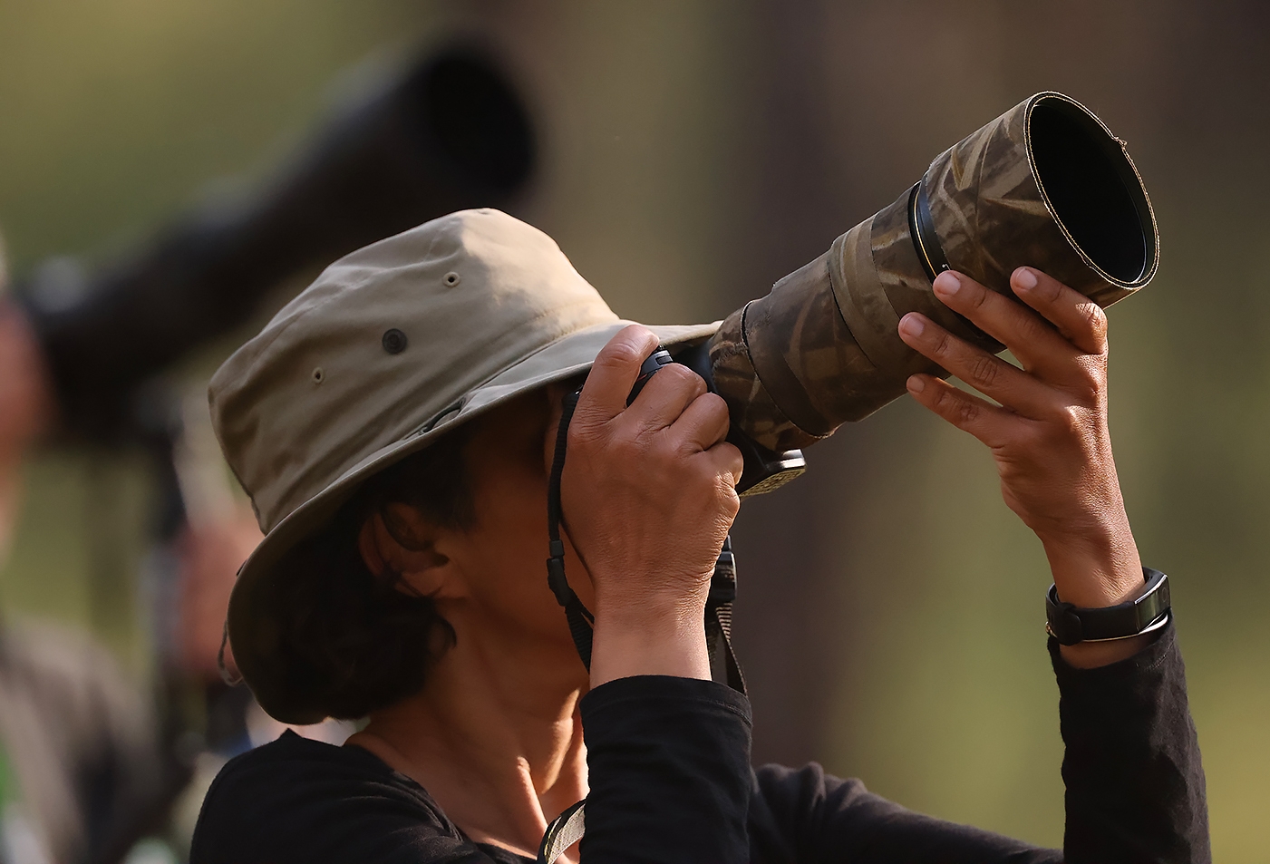 woman with telephoto lens taking photo pf birds