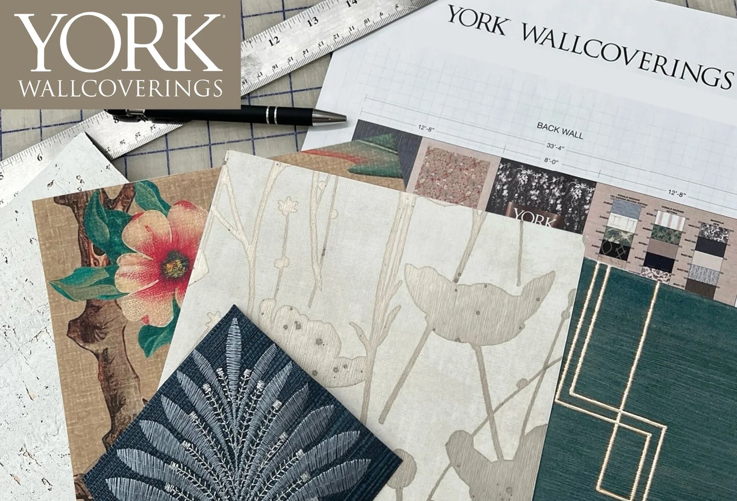 York Wallcoverings designer wallpaper samples with floral and geometric patterns on a project planning desk.