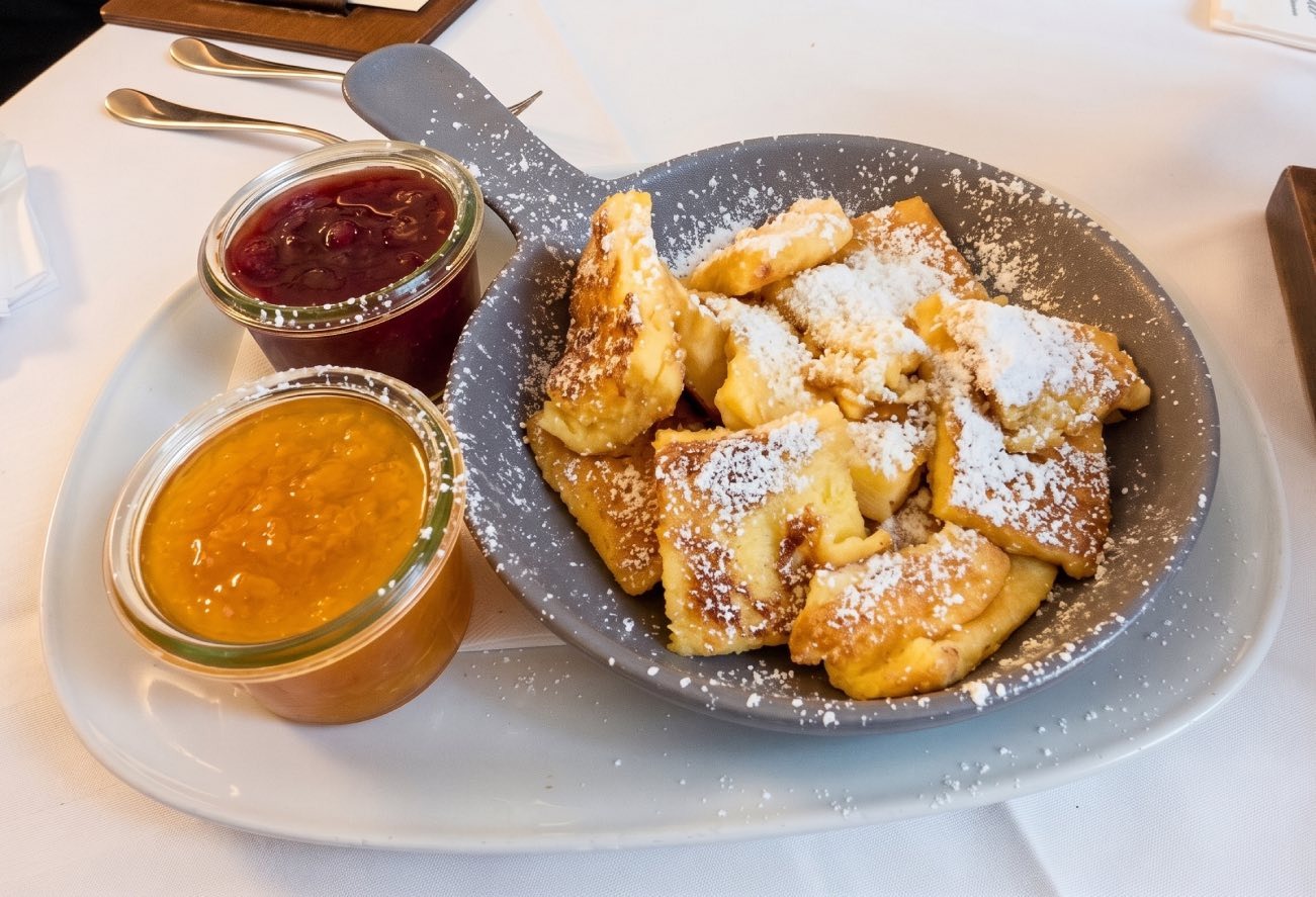 Una ración de Kaiserschmarrn caliente espolvoreado con azúcar glas en una sartén pequeña