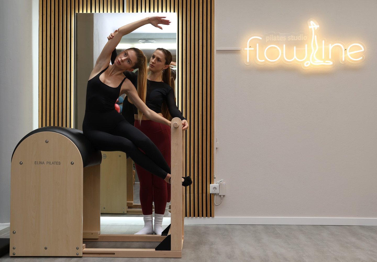 Pilates instructor assisting a student in a side stretch on the spine corrector in Pilates Studio