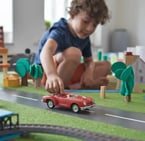 enfant qui joue avec une voiture rouge