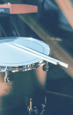 redish blue tint to upclose image of drums and drumsticks