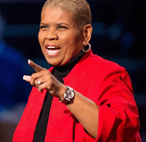 a woman in a red jacket and black top speaking to a crowd