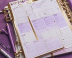 un cahier avec un bloc-notes et des stylos sur fond violet