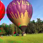 two hot air balloons in a field with a city skyline in the background