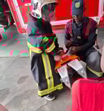 A professional firefighter helps a child from the creative workshop put on a firefighter uniform to 