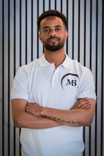 well lit Portrait photo of Ben, Co-owner of MB Barbers Manchester, posing with a smile and his arms crossed