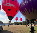 a man standing in front of a group of hot air balloons