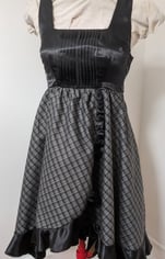 The front of a black/gold plaid and black satin flowy cocktail dress