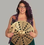 Rachel holding a cymbal with holes through out it, smiling