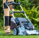 a man in a hat and gloves is using a lawn mower
