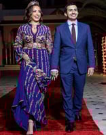 a man and woman in formal attire walking down a red carpet