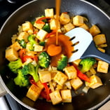 "Crispy tofu and vegetables simmering in sauce until thickened