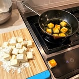 Cornstarch-coated tofu cubes frying until golden