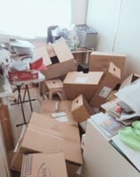 Cluttered sewing room with boxes and paperwork, needing organisation.