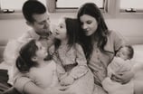 Black and white photo of the full family on the master bed during a Grand Rapids newborn session.