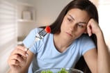 Menina segurando garfo com alimento, mas sem apetite