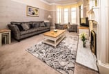 The spacious living room at Gourock Seaview Holiday Let with a couch, armchairs and a fireplace