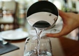 a person pouring water into a glass of water
