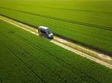 a van driving down a dirt road with a truck