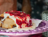cinnamon roll caindo muita cobertura de leite condensado e geléia de frutas vermelhas e morango