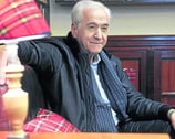 a man in a black jacket and tie dye on a chair