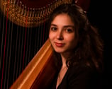 Headshot of a female harp player posing in front of her instrument