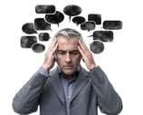 un homme e tenant la tete avec des pensées et un dialogue interieur negatif sous forme de bulle noir