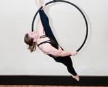 Vrouw in zwarte outfit voert een aerial hoop oefening uit bij De Polecats Fabriek in Gent